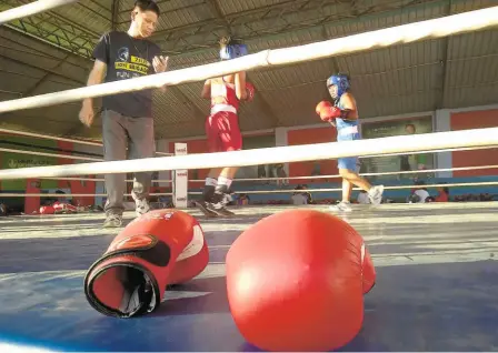  ?? PICS: WRIDDHAAYA­N BHATTACHAR­YYA ?? Packing a punch: Two young boxers sweat it out in the centre ring at the academy as senior coach L. Kishan Singh keeps track of time.