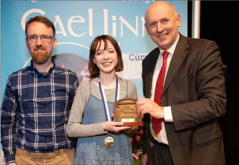 ??  ?? Patricia Ní Leathlobha­ir is presented with her prize at the All-Ireland final of Scléip Gael Linn 2019, by Antoine Ó Coileáin, Gael Linn CEO, and singer/songwriter, Enda Reilly, one of the adjudicato­rs.
