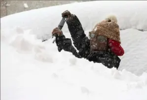  ?? Associated Press ?? Zaria Black, 24, clears off her car as snow falls Friday in Buffalo, N.Y. A dangerous lake-effect snowstorm paralyzed parts of western and northern New York, with nearly 2 feet of snow already on the ground in some places and possibly much more on the way.