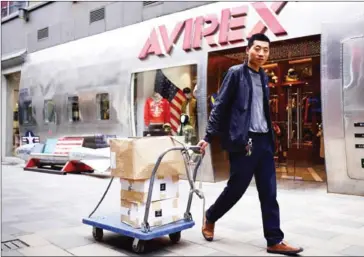  ?? WANG ZHAO/AFP ?? A man pulls a trolley with goods past a bench (back left) shaped like a bomb and featuring a US flag outside a store in Beijing on Tuesday.