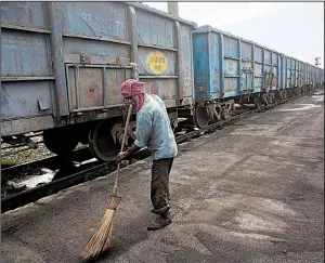  ?? AP/VAISHNAVEE SHARMA ?? A worker sweeps from New Delhi. up spilled petroleum coke in July at a rail yard in Rampur, India, about 130 miles