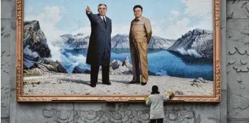  ??  ?? Die herrschend­e Clique feiert sich, den Menschen im Land fehlt es am Nötigsten: Eine Arbeiterin reinigt den Ramen eines riesigen Mosaiks, das die verstorben­en Diktatoren Kim Il Sung (links) und Kim Jong Il zeigt.