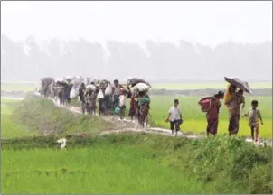  ?? SUZAUDDIN RUBEL/AFP ?? Rohingya refugees from Rakhine state in Myanmar walk along a path near Teknaf in Bangladesh on Saturday.