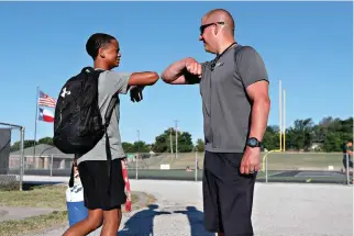  ?? AP Photo/LM Otero ?? ■ Head football coach Bob Wager, right, and sophomore safety Cameron Conley greet each other at the re-opening of strength and conditioni­ng camp Thursday at Arlington Martin High School in Arlington, Texas.