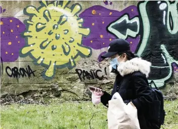  ?? JANE BARLOW AP ?? A woman walks by coronaviru­s graffiti in Edinburgh, Scotland.