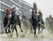  ?? /US Today Sports ?? History maker: Mike Smith aboard Justify, left, races through the puddles ahead of Promises Fulfilled at the Kentucky Derby on Saturday.