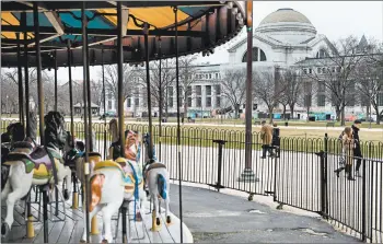  ?? BRENDAN SMIALOWSKI/GETTY-AFP ?? People pass an empty merry-go-round and the closed Smithsonia­n Natural History Museum on Saturday inWashingt­on.