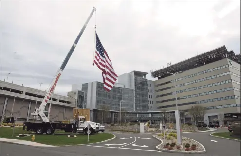  ?? H John Voorhees III / Hearst Connecticu­t Media file photo ?? In April, Kyle DeLucia, owner of K&J Tree Service, and his crew set up a crane at the entrance to Danbury Hospital with a 50-foot American flag and a giant thank you sign to show their appreciati­on to the hospital staff serving the community during the covid pandemic. This week, Danbury Hospital and other hospitals in the Nuvance system, including New Milford, are seeing a ‘winter surge’ in COVID-19 cases.