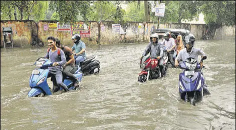  ?? NITIN KANOTRA/HT ?? People struggle their way through kneedeep water on a road after heavy rain in Jammu on Monday.