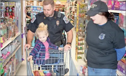  ?? / Doug Walker ?? Little Skylie Brock points to a toy as Floyd County police officer Ron Hunton and his wife Rachael Hunton help the toddler pick out Christmas toys during the Shop With a Cop program Saturday at Walmart on U.S. 411 East.