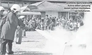  ??  ?? SEORANG guru wanita, Azlina diberi peluang dalam latihan memadam api kebakaran.