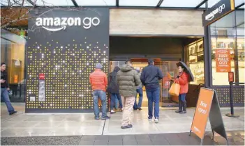  ?? — Reuters ?? People are offered free reusable bags as they enter the new Amazon Go store in Seattle, Washington.