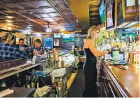  ?? VALAURIAN WALLER/NEW YORK TIMES ?? A bartender wearing a face mask serves patrons at a bar in the Rivertown neighborho­od of Detroit on Thursday. Gov. Gretchen Whitmer, a high-profile Democrat, is bucking the pleas of doctors and epidemiolo­gists in her state and instead asking for voluntary actions from the public to control the virus’s spread.