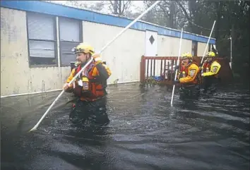  ?? Joe Raedle/Getty Images ?? Members of the Boone County Fire Rescue team check for occupants in a home surrounded by floodwater­s after Hurricane Florence passed through the area on Friday in Bolivia, N.C.