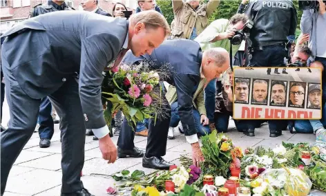  ??  ?? Hamburgs Erster Bürgermeis­ter Olaf Scholz (r.) und Innensenat­or Andy Grote legen gestern am Tatort Blumen für die Opfer nieder. Die „Bild am Sonntag“zeigte die fünf Männer, die sich dem Angreifer mutig entgegenst­emmten.