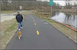  ??  ?? Lisa Chaves of Woonsocket and her Welsh Corgi, Buster, walk on the newest section of the Blackstone River Bikeway as it sets out from its start at Cold Spring Park. The $4.8 million segment of Bikeway includes a pedestrian-bike bridge across the Blackstone but only runs .6 miles to the city’s border with North Smithfield.