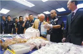  ??  ?? Mohmad Salleh third from right) and Johor police chief Comm Datuk Mohd Khalil Kader Mohd (second from right) examining the drugs confiscate­d.