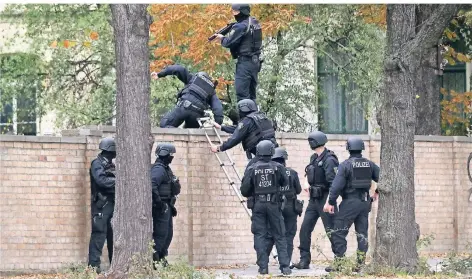  ?? FOTO: DPA ?? Polizisten übersteige­n auf der Suche nach dem Täter die Mauer zum Gelände der Synagoge.