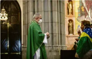  ?? Eduardo Knapp/Folhapress ?? Padre Luiz Eduardo Baronto entrega hóstia a fiel em missa na Catedral da Sé