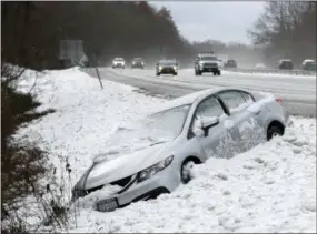  ?? FRANK BACERRA JR./THE JOURNAL NEWS VIA AP ?? This Thursday photo shows traffic passing by as a car that went off Interstate 684, at the Goldens Bridge exit, during a snowstorm. The first snowfall of the season lingered Friday in the Northeast as thousands of exhausted commuters pointed their fingers at politician­s and meteorolog­ists for leaving them creeping along highways or stuck in mass transit hubs.