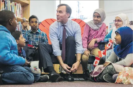  ?? MARK BLINCH/THE CANADIAN PRESS ?? Finance Minister Bill Morneau takes part in the pre-budget ceremony of putting on new shoes at Nelson Mandela Park Public School in Toronto on Monday. Morneau says the budget will introduce “new measures that will be important for Canadian families.”