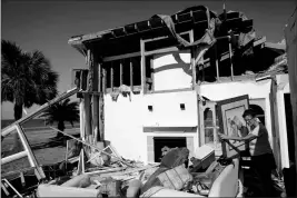  ?? ASSOCIATED PRESS ?? out of the rubble of her damaged home from Hurricane Michael in Mexico Beach, Fla., on Sunday. Trump says climate change not a hoax, not sure of its source