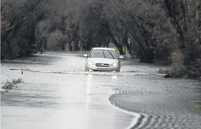  ?? EFE / ELISEO TRIGO ?? Un coche cruza la carretera inundada LU-P-1701 en la localidad gallega de Muimenta (Lugo), ayer.