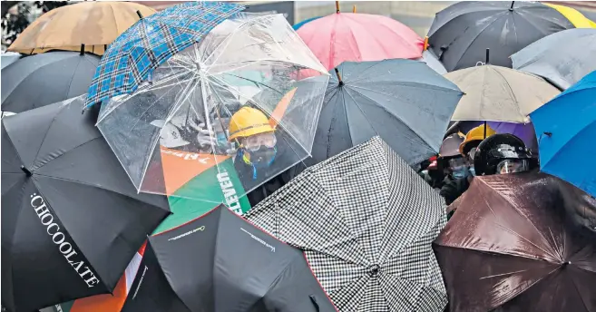  ??  ?? Protesters use umbrellas to protect themselves from police
spray