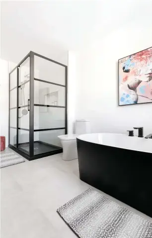  ??  ?? La douche de style verrière d'atelier et le bain à l'enveloppe noire sont aussi au sommet des tendances ! Pour créer un contraste avec les éléments foncés de la salle de bain, les designers ont opté pour une céramique gris pâle au sol.