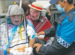  ??  ?? A police officer checks the temperatur­e of a performer before he participat­es in La Diablada Pillarena.