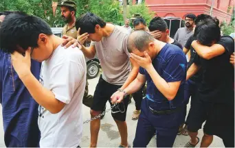  ?? AP ?? Detained Chinese nationals, accused of luring Pakistani girls and women into fake marriages, being escorted by Federal Investigat­ion Agency officers to court in Lahore.