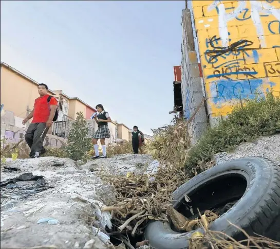  ?? Don Bartletti Los Angeles Times ?? SCHOOLCHIL­DREN WALK along a trash-strewn, rutted alley between row houses in the blighted Cañadas del Florido neighborho­od in Tijuana.