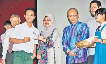  ??  ?? Fatimah (centre) presents cash assistance to a student while (from second right) Ting, Yong and others look on.