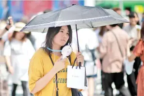  ?? — Gambar AFP ?? SEORANG wanita menggunaka­n kipas angin kecil untuk menyejukka­n badannya di Tokyo semalam akibat gelombang haba ‘luar biasa’ melanda Jepun sejak awal bulan ini.