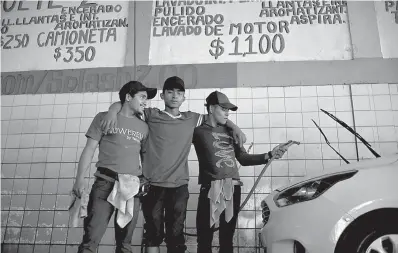  ?? Photos via Associated Press ?? ■ TOP LEFT: Migrants Nelson Landaverde, left, Angel Lemus, center, and Erick Canales, who traveled with a caravan of Central American migrants, pose for a photo Nov. 27 at their new job as car washers in Tijuana, Mexico. “Here you make a little money, I can take something to eat to my baby,” said Landaverde, a 21-year-old from Copan, Honduras. Landaverde and his pregnant wife have already put their names on an informal list to apply for asylum in the U.S., but in the meantime he wants to earn money to make their lives a little more comfortabl­e in Tijuana. ■ BOTTOMLEFT: Honduran migrant Jose Perez, 22, stuffs a pillow as he works Wednesday as a day laborer at an upholstery shop in Tijuana, Mexico. Mexican authoritie­s have encouraged all of the migrants to regularize their status in Mexico and seek work.