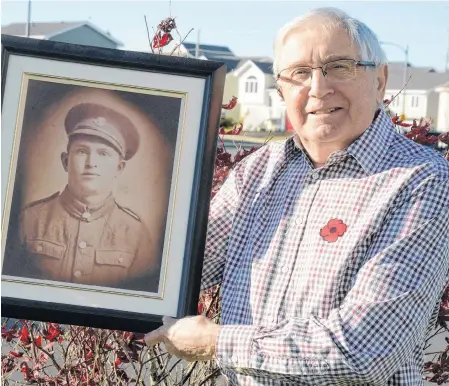  ?? JOE GIBBONS/THE TELEGRAM ?? Retired Anglican minister Rev. Eugene Castella holds a photo of his late father, Reuben Castella, outside his home on Monday afternoon.