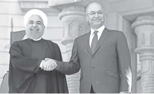  ?? AP Photo/KhAlid MohAMMed ?? IraqI President Barham Salih, (right), shakes hands with visiting Iranian President Hassan rouhani at Salam Palace in Baghdad, Iraq, on Monday, March 11. rouhani arrived in Baghdad on Monday, making his first official visit to the nation that Tehran once fought a bloody war against.