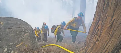  ?? JAE C. HONG/ASSOCIATED PRESS ?? Firefighte­rs hike up a mountain while battling the Caldor Fire on Friday in South Lake Tahoe, Calif. Crews took advantage of decreasing winds to battle a California wildfire near Lake Tahoe and were even able to allow some people back to their homes.