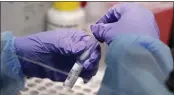  ?? CHARLES KRUPA — THE ASSOCIATED PRESS FILE ?? James Robson, a biomedical engineerin­g graduate student, holds a swab and specimen vial in the new COVID-19, oncampus testing lab at Boston University in Boston.