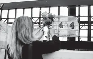  ?? Federico Cosso / Associated Press ?? A relative of a crewman of the ARA San Juan submarine ties a bouquet of flowers Saturday at a naval base in Mar del Plata, Argentina, accepting that the 44 sailors died at sea.