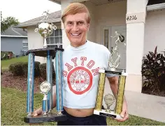  ?? PHOTO BY STEPHEN M. DOWELL/ORLANDO SENTINEL/TNS ?? Denny Fryman holds trophies for his 500th and 1,000th marathons outside his home. He has completed 1,001 marathons and still counting.