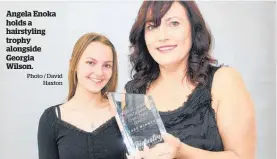  ?? Photo / David Haxton ?? Angela Enoka holds a hairstylin­g trophy alongside Georgia Wilson.