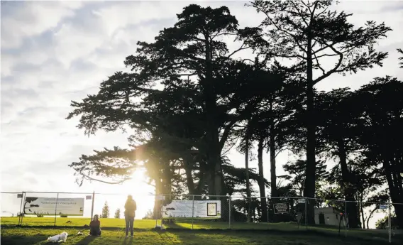  ?? Photos by Gabrielle Lurie / The Chronicle ?? Visitors relax Wednesday outside a fence at Alamo Square Park, which is awaiting work that was expected to take seven months but could take more than a year.