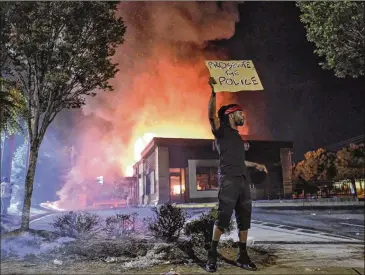  ?? BEN GRAY / FOR THE AJC ?? The Wendy’s restaurant where Rayshard Brooks was killed by a cop was torched the night after Brooks’ death, and America watched on CNN as flames engulfed it. The charred, graffiti-scrawled ruins have since become part shrine to a Black man’s death, and part Occupy Atlanta — the University Avenue branch.