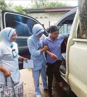  ??  ?? Sarina Hashim (right) and Zuhana Ariffin helping Zulaiha Solek to board the 4WD in Kampung Permatang Siput, Pekan, yesterday.