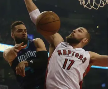  ?? RICK MADONIK/TORONTO STAR ?? Charlotte’s Jeff Taylor dishes off under the hoop around Raptors’ centre Jonas Valanciuna­s.