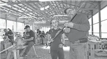  ?? PAUL A. SMITH / MILWAUKEE JOURNAL SENTINEL; ?? Instructor Perry Anderson inspects a self bow made by Calla Fritz of Big Bend, at Bow Jam at Ojibwa Bowhunters.