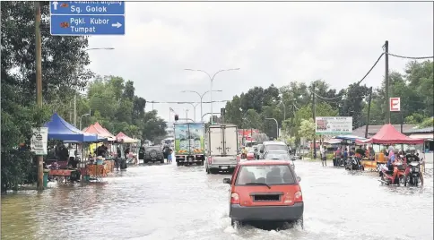  ??  ?? Vehicles were through the flood waters in Rantau Panjang town. — Bernama photo