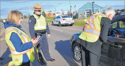  ?? ERIC MCCARTHY/JOURNAL PIONEER ?? Vice-president of the West Prince chapter of MADD Canada, Trudy Betts, and Cst. Al McGrath from West Prince RCMP, look on as Rural and Regional Developmen­t Minister Pat Murphy passes out red ribbons to motorists. MADD and RCMP conducted a traffic stop...