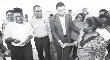  ?? RICARDO MAKYN/MULTI MEDIA PHOTO EDITOR ?? Chairman of the NHT Ambassador Dr Nigel Clarke (second left) and Prime Minister Andrew Holness (centre) surrrounde­d by beneficiar­ies at the handover of keys for the Berkshire Court developmen­t in Spanish Town last Friday.